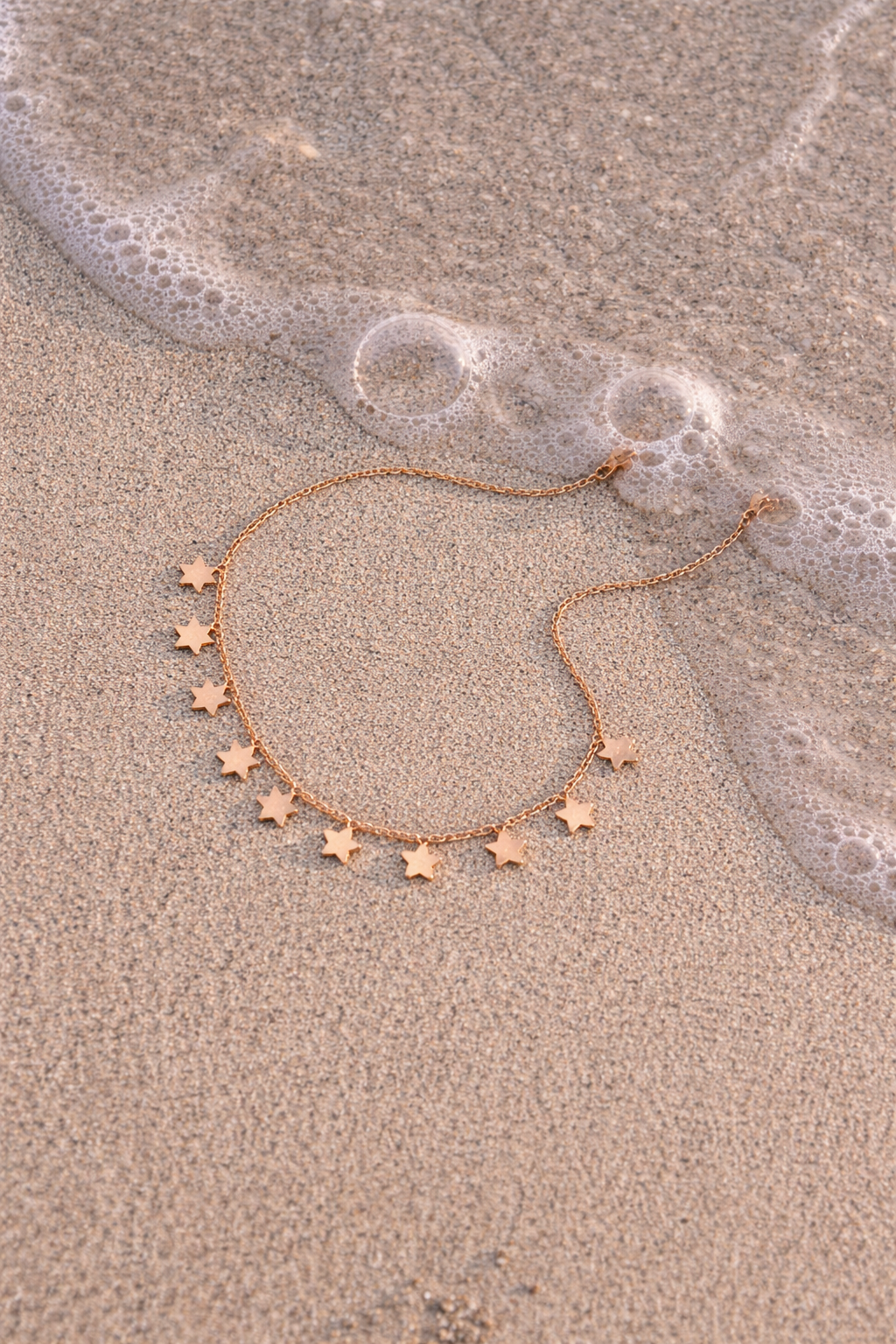 Star-shaped necklace on wet sand with ocean waves