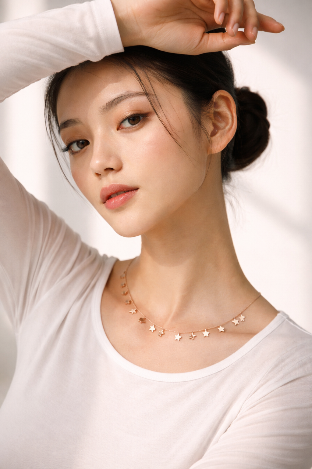 Woman wearing a delicate necklace against a white background