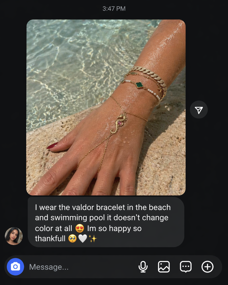 Hand wearing gold bracelets with a scenic background of water and sand.