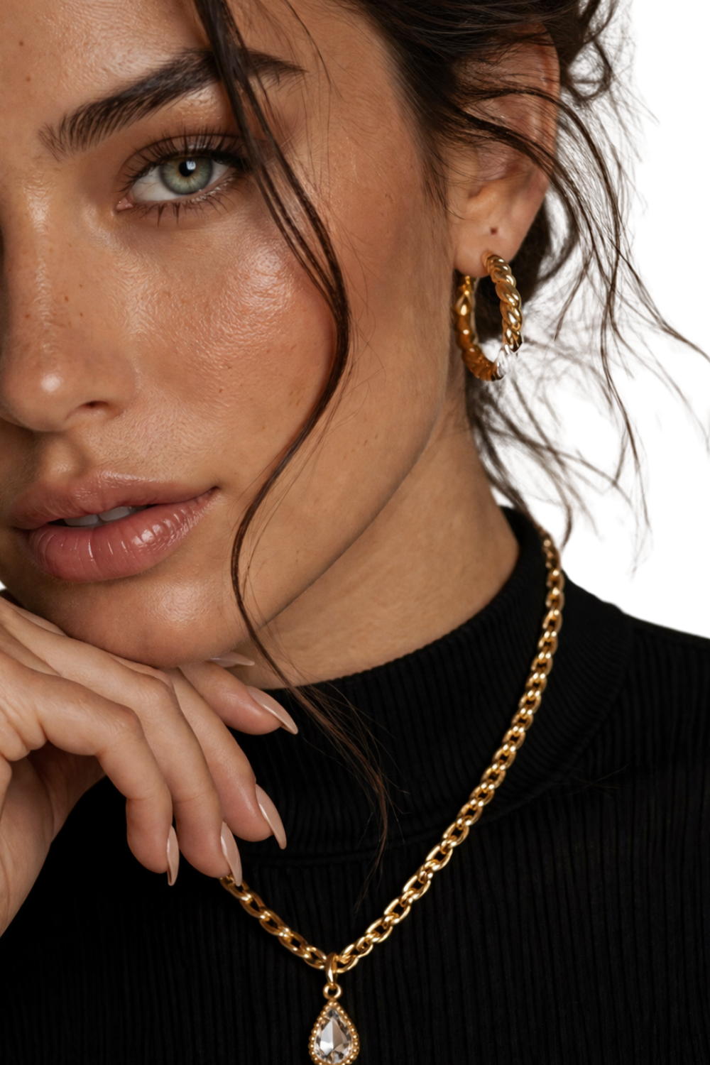 The Valdor fine jewelry  close-up of elegant woman wearing gold chain necklace with pendant and textured hoop earrings, inspired by Italian luxury craftsmanship